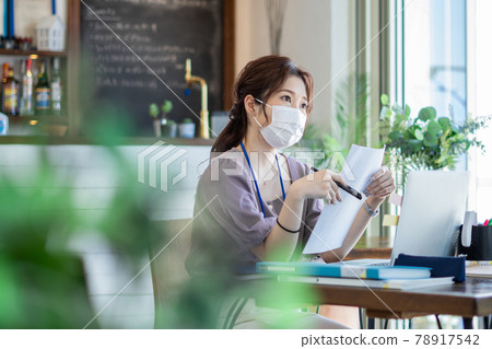 一個戴著面具在咖啡館式辦公室工作的女人 78917542