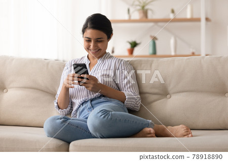 Smiling Indian woman use cellphone browsing internet Smiling Indian woman use cellphone browsing internet 78918890