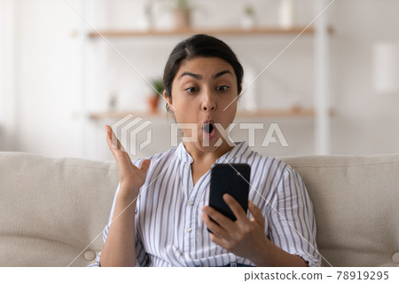 Young Indian woman shocked by news on cellphone 78919295