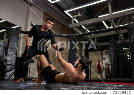 Side view on Mixed martial artists during fight, help each other, in ring at gym 78919437