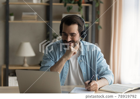Happy young man listening educational online lecture on computer. Happy young man listening educational online lecture on computer. 78919792
