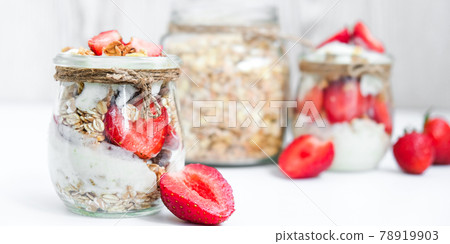 Healthy breakfast. Oatmeal Granola with greek yogurt and nuts strawberry muesli in jars on light background. Vegan, vegetarian and weight loss diet concept. Detox menu. Healthy breakfast. Oatmeal Granola with greek yogurt and nuts strawberry muesli in jars on light background. Vegan, vegetarian and weight loss diet concept. Detox menu. 78919903