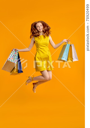 happy redhead lucky woman jumping having fun with shopping packages in hands happy redhead lucky woman jumping having fun with shopping packages in hands 78920499