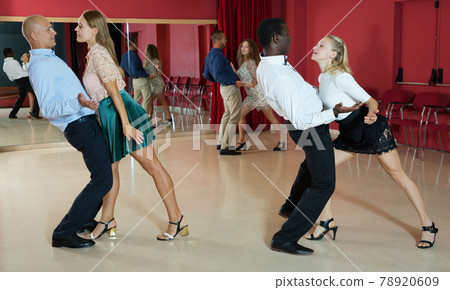 Adult pairs dancing tango movements in modern dance studio Adult pairs dancing tango movements in modern dance studio 78920609