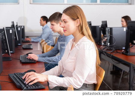 Side view of focused female and male students working on computers in classroom 78920779
