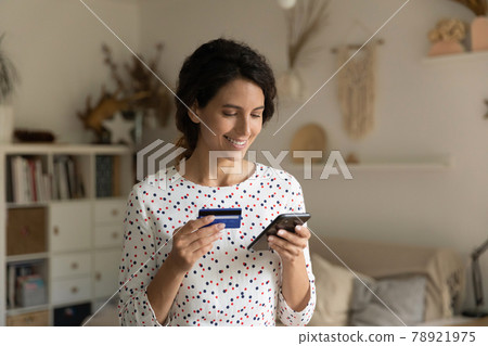 Smiling woman paying online by credit card, using smartphone 78921975