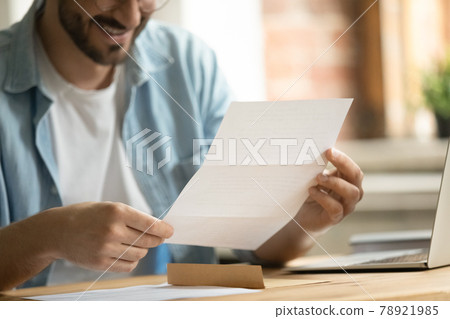 Close up young man holding paper correspondence in hands. 78921985