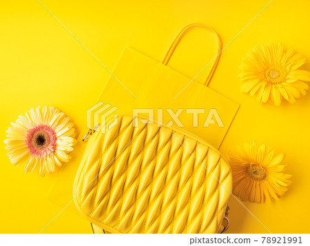Yellow fashion lady handbag with gerbera flowers on monochrome background with paper shopping bag Yellow fashion lady handbag with gerbera flowers on monochrome background with paper shopping bag 78921991