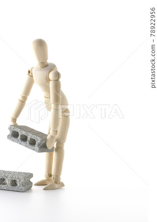 在白色背景上拍攝了一個攜帶混凝土塊的繪圖娃娃。 在白色背景上拍攝了一個攜帶混凝土塊的繪圖娃娃。 78922956