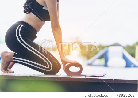Woman hands rolled up yoga mat outdoor workout. Close up hands rolling foam yoga gym mat outside morning exercise. Woman stretching workout sportive healthy lifestyle on street city town park concept Woman hands rolled up yoga mat outdoor workout. Close up hands rolling foam yoga gym mat outside morning exercise. Woman stretching workout sportive healthy lifestyle on street city town park concept 78923265