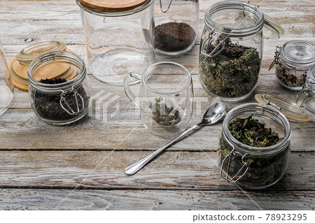 Double wall glass tea cup and ingredients for herbal teas on a wooden rustic background. Healing tea from wild plants. Glass sealed jars for storing food. Wild natural herbs. Copy space Double wall glass tea cup and ingredients for herbal teas on a wooden rustic background. Healing tea from wild plants. Glass sealed jars for storing food. Wild natural herbs. Copy space 78923295