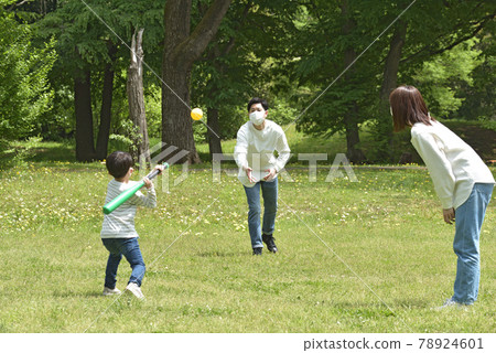 A family wearing a mask and enjoying baseball in the park 78924601