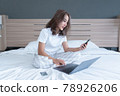 woman lying down the bed with laptop and phone 78926206