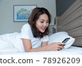 Young woman using smartphone on bed 78926209