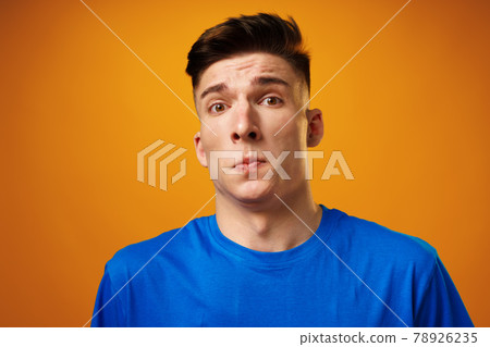 Portrait of crazy amazed young man in blue t-shirt against yellow background 78926235