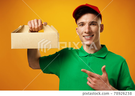 Delivery person holding parcel with food delivery against yellow background Delivery person holding parcel with food delivery against yellow background 78926238