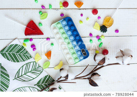 Phone case with pop it on white wooden background Phone case with pop it on white wooden background 78928044