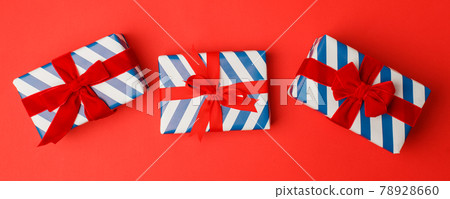 4th of July American Independence Day. Happy Independence Day. White blue stripe gift boxes with red bow on red background. Flat lay, top view, copy space, banner, copy space, sale, Christmas 4th of July American Independence Day. Happy Independence Day. White blue stripe gift boxes with red bow on red background. Flat lay, top view, copy space, banner, copy space, sale, Christmas 78928660