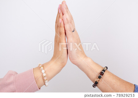 Hands and arms of men and women wearing gemstone bracelets 78929253