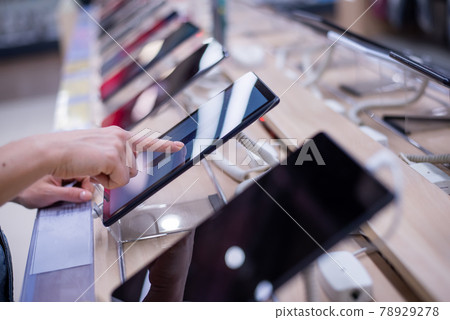 Faceless caucasian woman chooses a smartphone in an electronics store. Close-up of a female hand with a phone tester 78929278