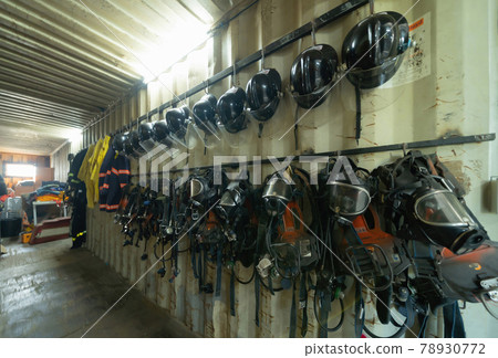 Firefighter or fireman safety protection tools, extinguisher, uniform in a gear storage room, an emergency accident rescue safety and security equipment 78930772