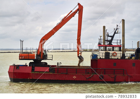 An excavator loads sand into a dredger An excavator loads sand into a dredger 78932833