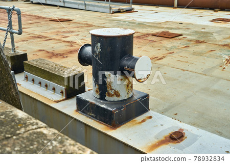 Side view of a cruciform mooring bollard showing signs of wear from ropes 78932834