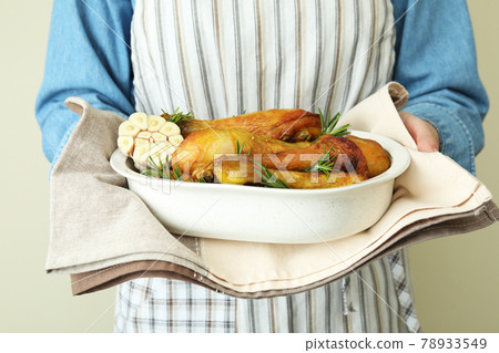 Woman hold baking tray with roast chicken drumsticks 78933549