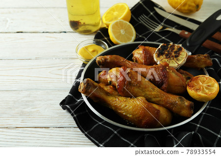 Concept of delicious eating with pan of roast chicken drumsticks on white wooden table Concept of delicious eating with pan of roast chicken drumsticks on white wooden table 78933554