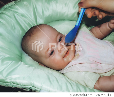 Mom feeds the baby with baby food 78938914