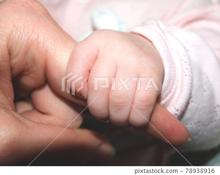 A baby with a small hand holds mom's finger 78938916