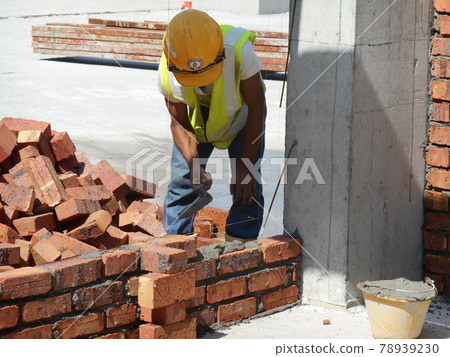 JASIN, MALAYSIA -SEPTEMBER 09, 2016: Brick walling joint and workmanship under construction at the construction site. Clay brick was attached together using cement mortar. JASIN, MALAYSIA -SEPTEMBER 09, 2016: Brick walling joint and workmanship under construction at the construction site. Clay brick was attached together using cement mortar. 78939230