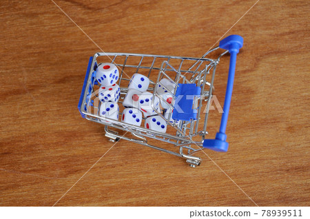 White dice in toy shopping trolley on wood texture background. White dice in toy shopping trolley on wood texture background. 78939511