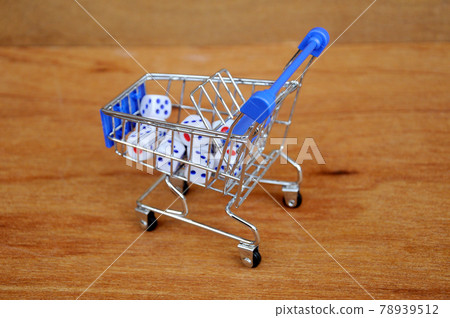 White dice in toy shopping trolley on wood texture background. White dice in toy shopping trolley on wood texture background. 78939512