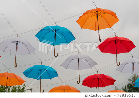 Colorful umbrellas hanging against overcast sky at outdoor festival Colorful umbrellas hanging against overcast sky at outdoor festival 78939513