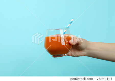 Female hand hold glass of juice on blue background 78940101