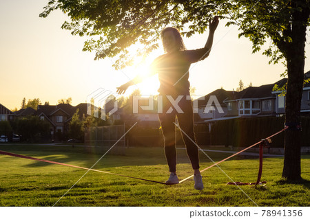 Adventurous White Caucasian Adult Woman walking on a Slackline Adventurous White Caucasian Adult Woman walking on a Slackline 78941356