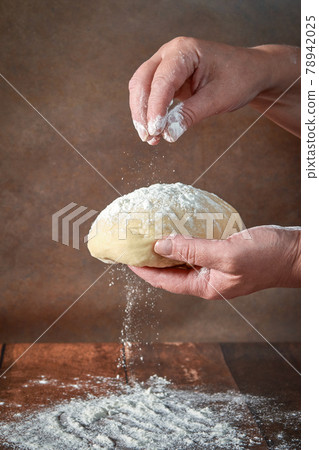 The hands of an elderly, plump woman are kneading dough on a wooden table. Preparation of dough for a festive cake, pizza The hands of an elderly, plump woman are kneading dough on a wooden table. Preparation of dough for a festive cake, pizza 78942025