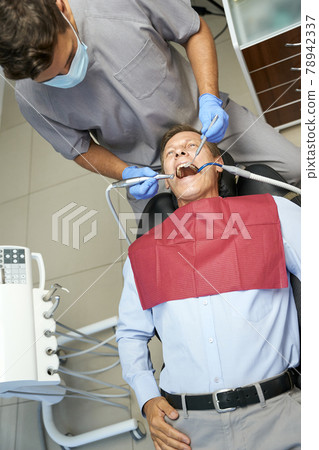 Qualified dentist monitoring teeth of his male patient 78942337