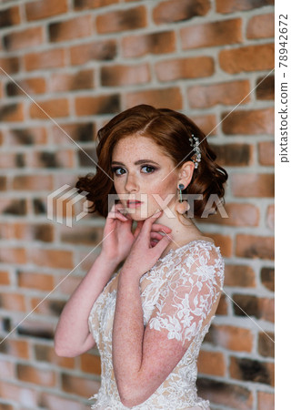 Portrait of red haired girl wearing wedding dress against a white studio background. 78942672
