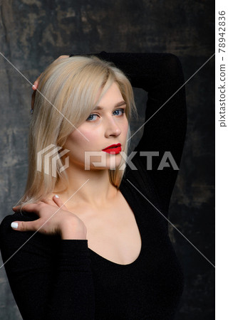 Young blonde plump woman with bright makeup in black bodysuit at dark background 78942836