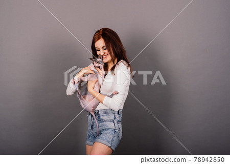 Gorgeous brunette woman smiling, holding Sphynx kitten, posing on grey and yellow studio background. Gorgeous brunette woman smiling, holding Sphynx kitten, posing on grey and yellow studio background. 78942850
