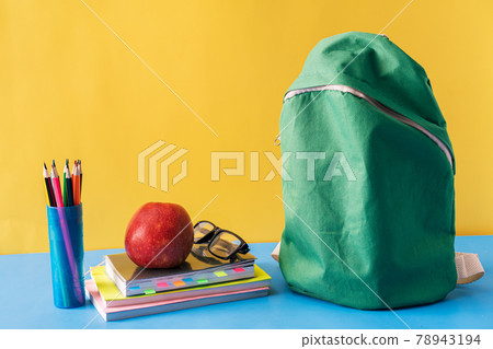 School supplies and green backpack on blue background 78943194