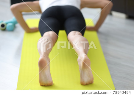 Young sportive woman doing push-ups on mat at home Young sportive woman doing push-ups on mat at home 78943494