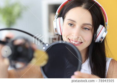 Portrait of young woman in headphones in front of microphone Portrait of young woman in headphones in front of microphone 78943505