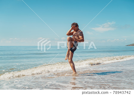 A muay thai or kickboxer training with shadow boxing outdoor at seashore 78943742