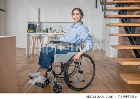Positive handicapped young woman at home and looking happy Positive handicapped young woman at home and looking happy 78944589