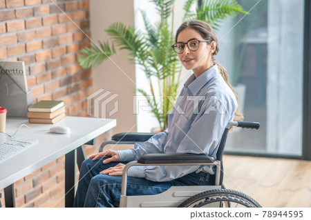 Young dark-haired handicapped woman looking thoughtful Young dark-haired handicapped woman looking thoughtful 78944595