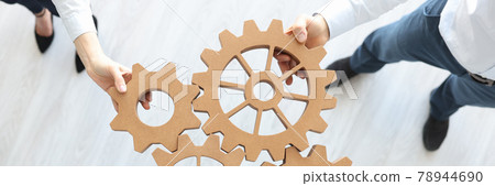 Group of business people stacking wooden gears top view 78944690