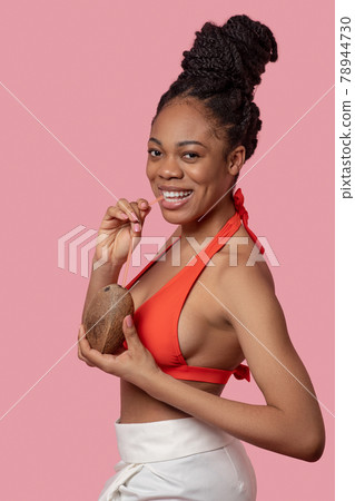 Dark-skinned woman holding coconut and looking happy 78944730